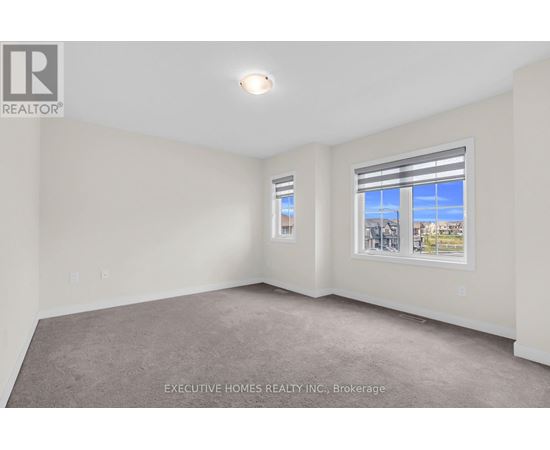 A room with a carpet floor and a window showing a view of buildings outside.