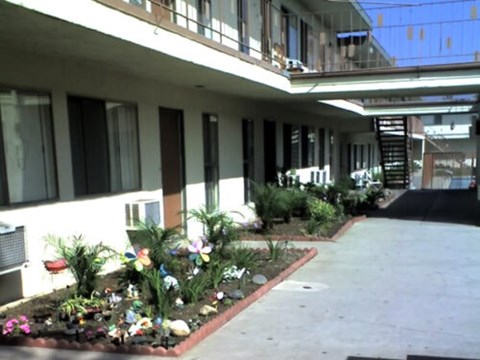 A building with a balcony and a flower bed in front.