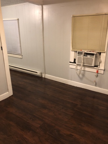 A room with a window and a wall-mounted air conditioning unit.