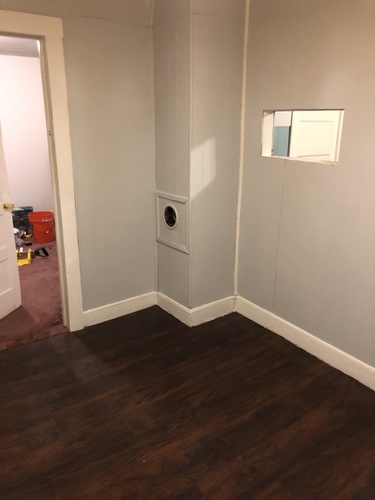 A white door with a round window in the middle of a room with wood flooring.