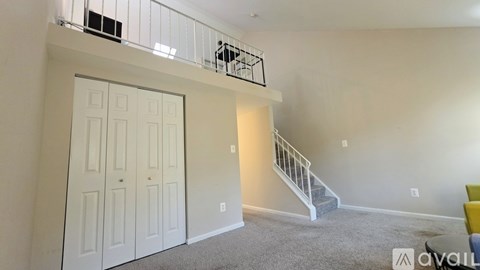 A spacious room with a staircase and a white door.