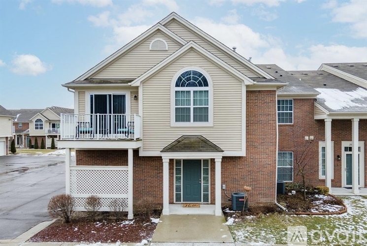 A two-story house with a balcony and a brick facade.