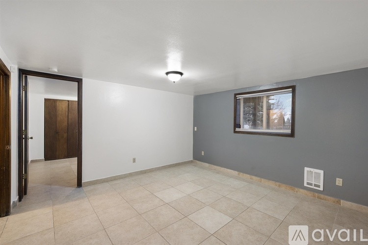 A room with a tiled floor and a window with blinds.