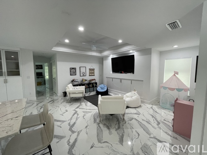 A living room with a marble floor and a television on the wall.