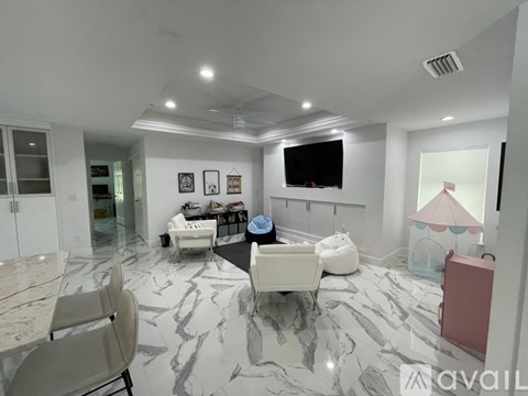 A living room with a marble floor and a television on the wall.