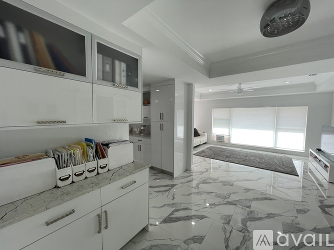 A kitchen with white cabinets and a marble floor.