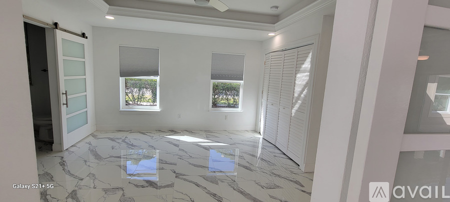 A spacious room with a marble floor and a large window.