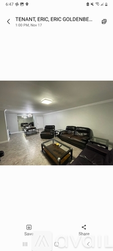 A living room with a black couch and a glass coffee table.
