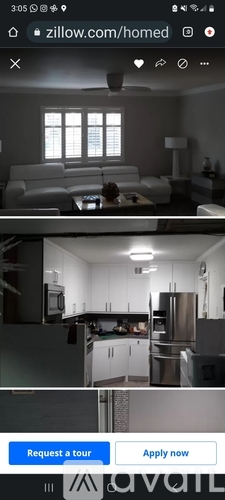 A modern living room with a white couch and a kitchen with stainless steel appliances.