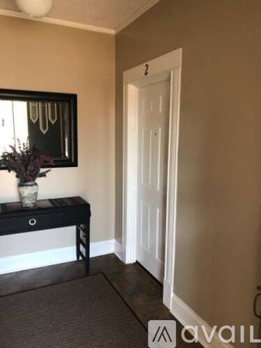 A hallway with a door and a table with a vase on it.