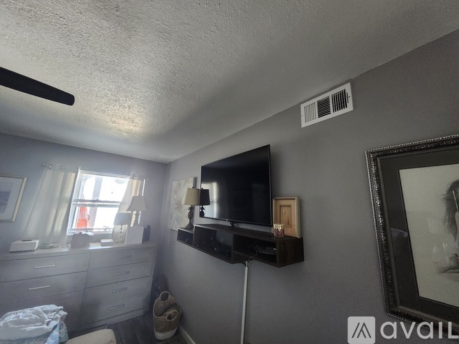 A bedroom with a bed, dresser, and a television on the wall.