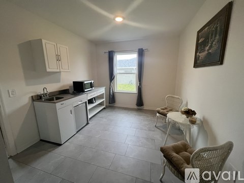A kitchen with a microwave, oven, sink, and a dining table with chairs.
