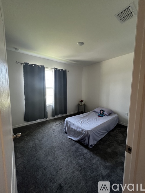 A bedroom with a bed, nightstand, and window with curtains.
