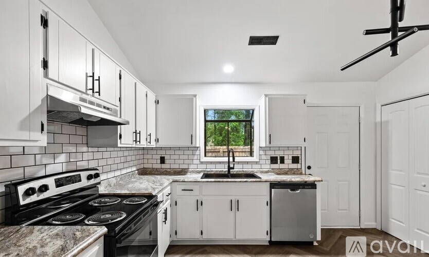 A kitchen with white cabinets and a window.