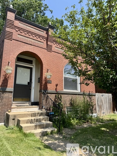 A red brick house with a black door and a small porch.