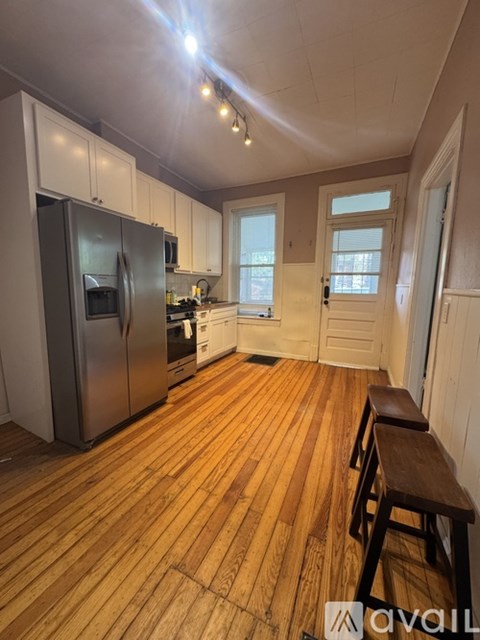 A kitchen with wooden floors and white cabinets.