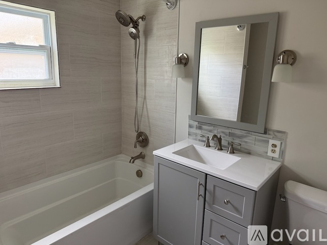 A bathroom with a white tub, sink, and mirror.