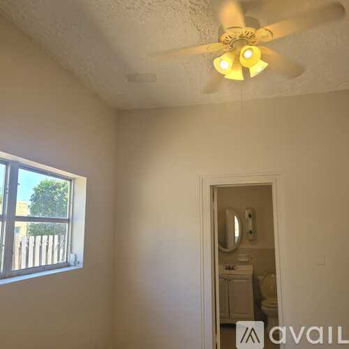 A room with a ceiling fan and a window.