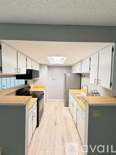 A kitchen with white cabinets and a wooden counter top.