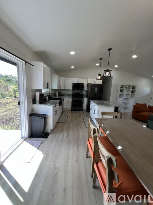 A modern kitchen with wooden floors and a dining area with orange chairs.