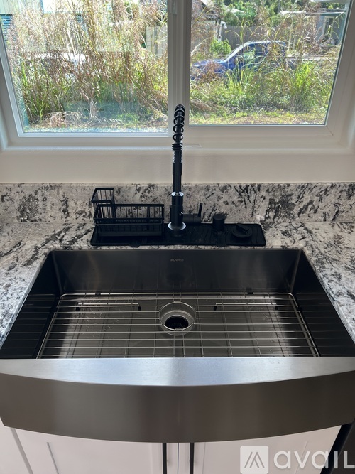 A kitchen sink with a black faucet and a black holder on the counter.