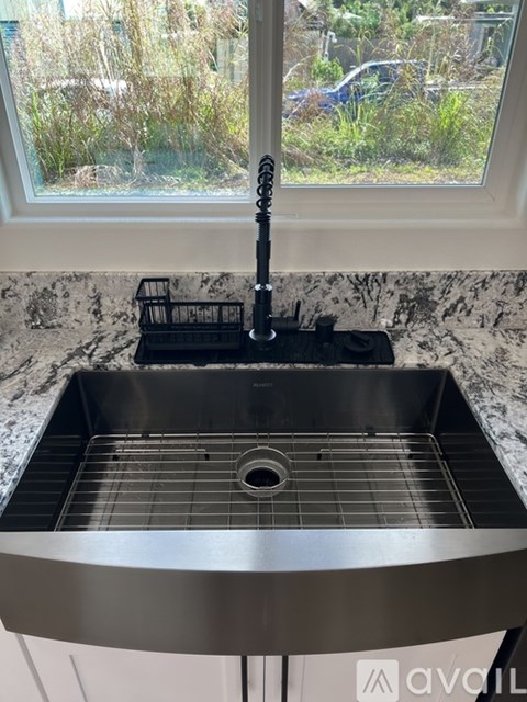 A kitchen sink with a black faucet and a black holder on the counter.