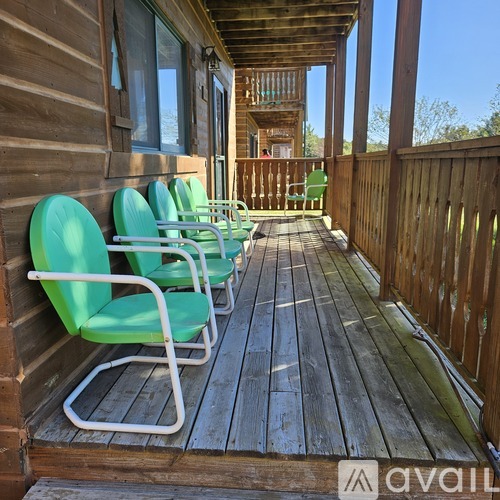 A wooden deck with green chairs and a railing.