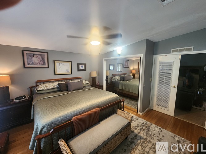 A bedroom with a bed, a chair, and a ceiling fan.