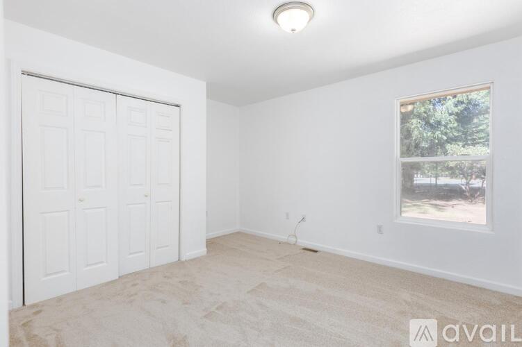 A room with a white door, a window, and a carpeted floor.