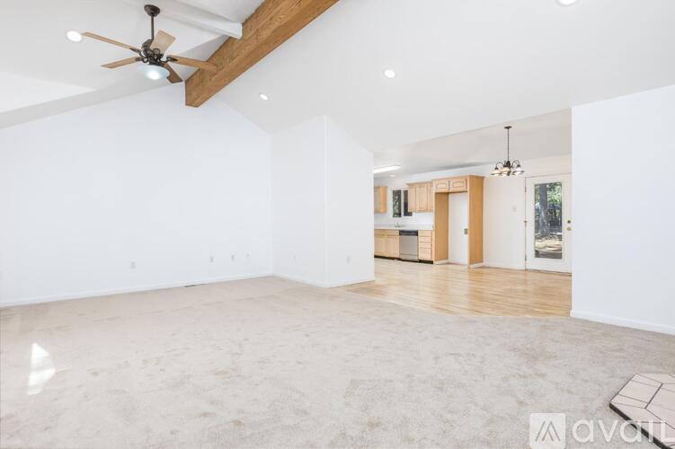 A spacious room with a ceiling fan and a rug on the floor.
