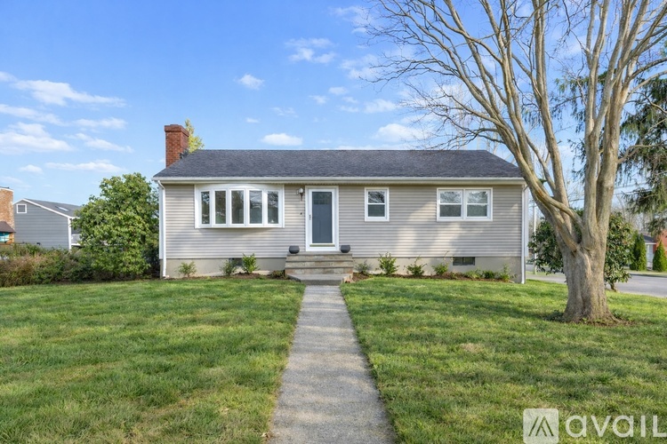 A house with a grey roof and a tree in front of it.