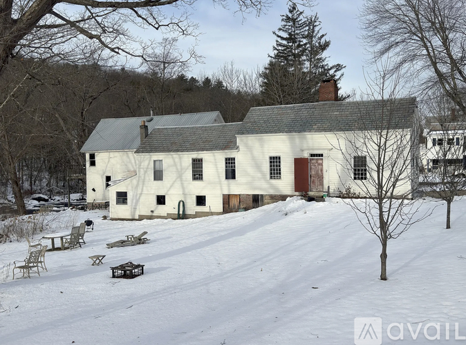 A large white house with a red door sits in the snow.