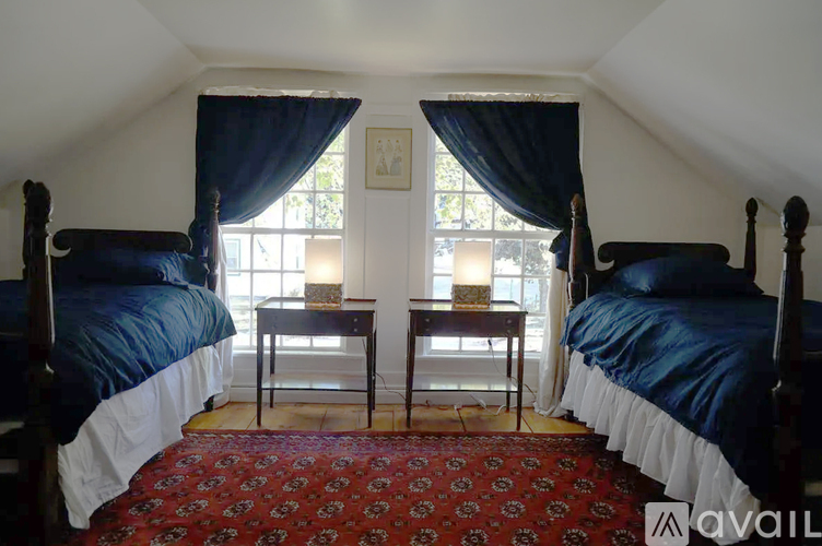 A bedroom with two beds and a red carpet.