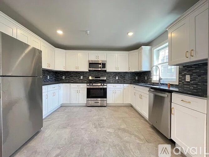 A kitchen with white cabinets and a stainless steel refrigerator.