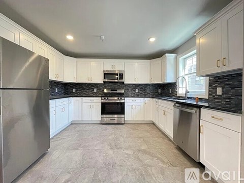 A kitchen with white cabinets and a stainless steel refrigerator.