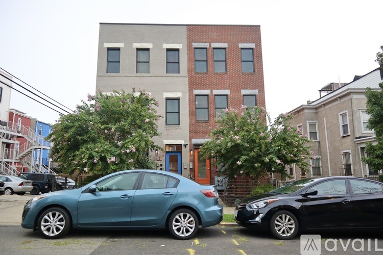 A blue car is parked in front of a grey building.