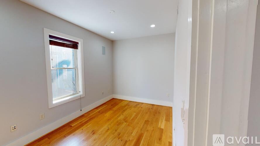 A room with wooden flooring and a window with blinds.