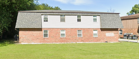 A red brick building with a grey roof and white shutters.