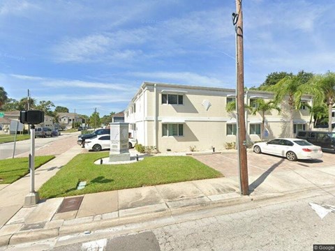 A street view of a residential area with a house, cars, and a traffic light.