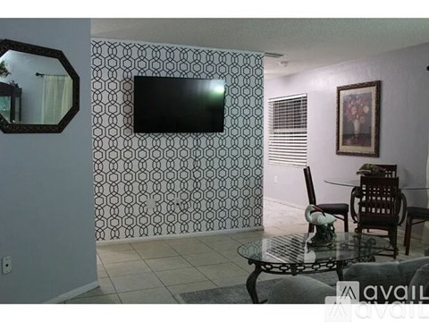 A living room with a television and a glass table.