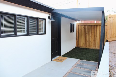 A white house with a black door and a brown wooden fence.