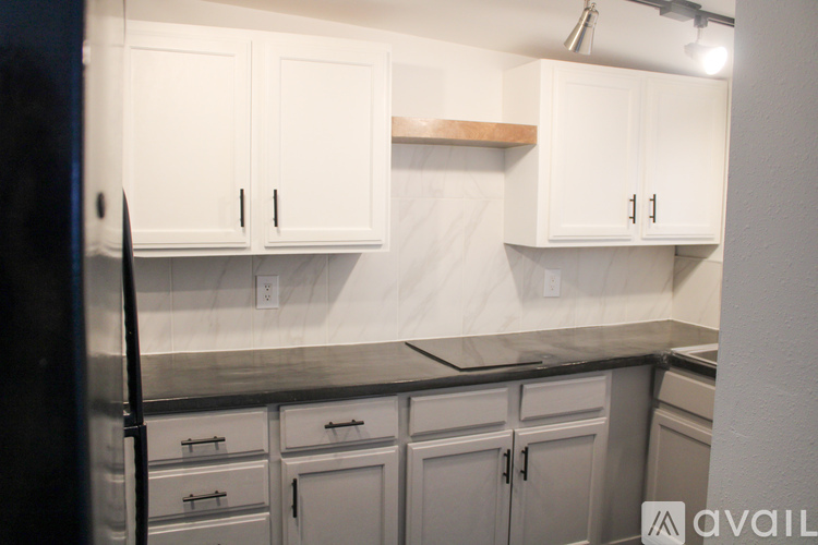 A kitchen with white cabinets and a black refrigerator.