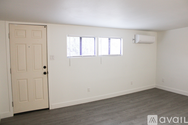 A room with a door, two windows, and a wall-mounted air conditioner unit.