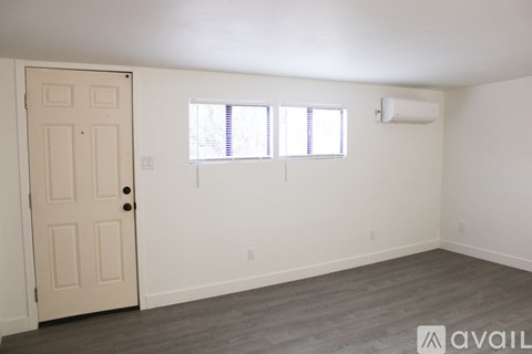 A room with a door, two windows, and a wall-mounted air conditioner unit.