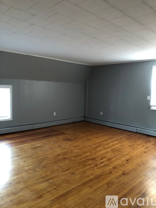A room with wooden flooring and a window on the left side.