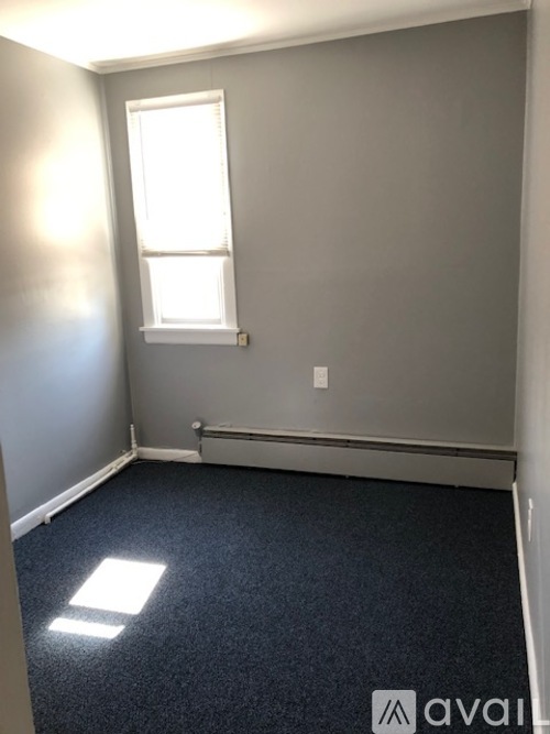 A room with a window and a carpeted floor.