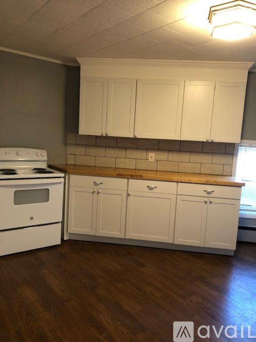 A kitchen with white cabinets and a stove top oven.
