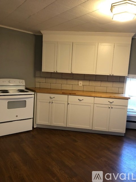 A kitchen with white cabinets and a stove top oven.