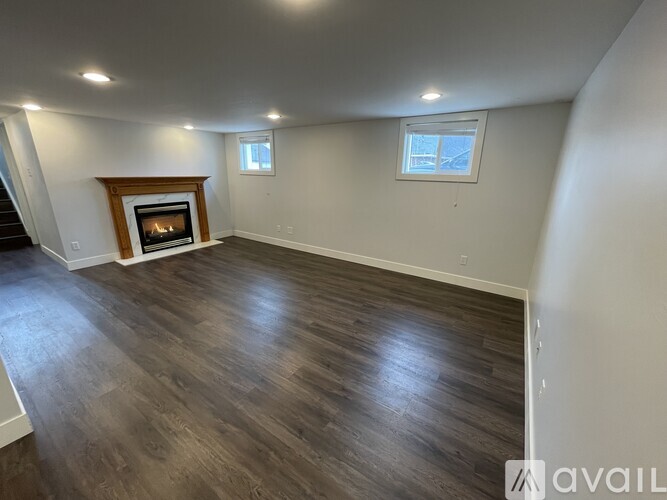 A spacious room with a fireplace and wood flooring.