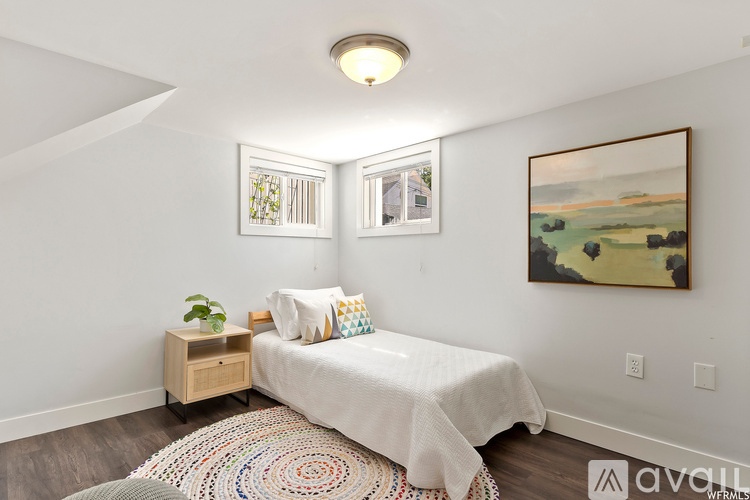 A bedroom with a bed, a nightstand, and a painting on the wall.